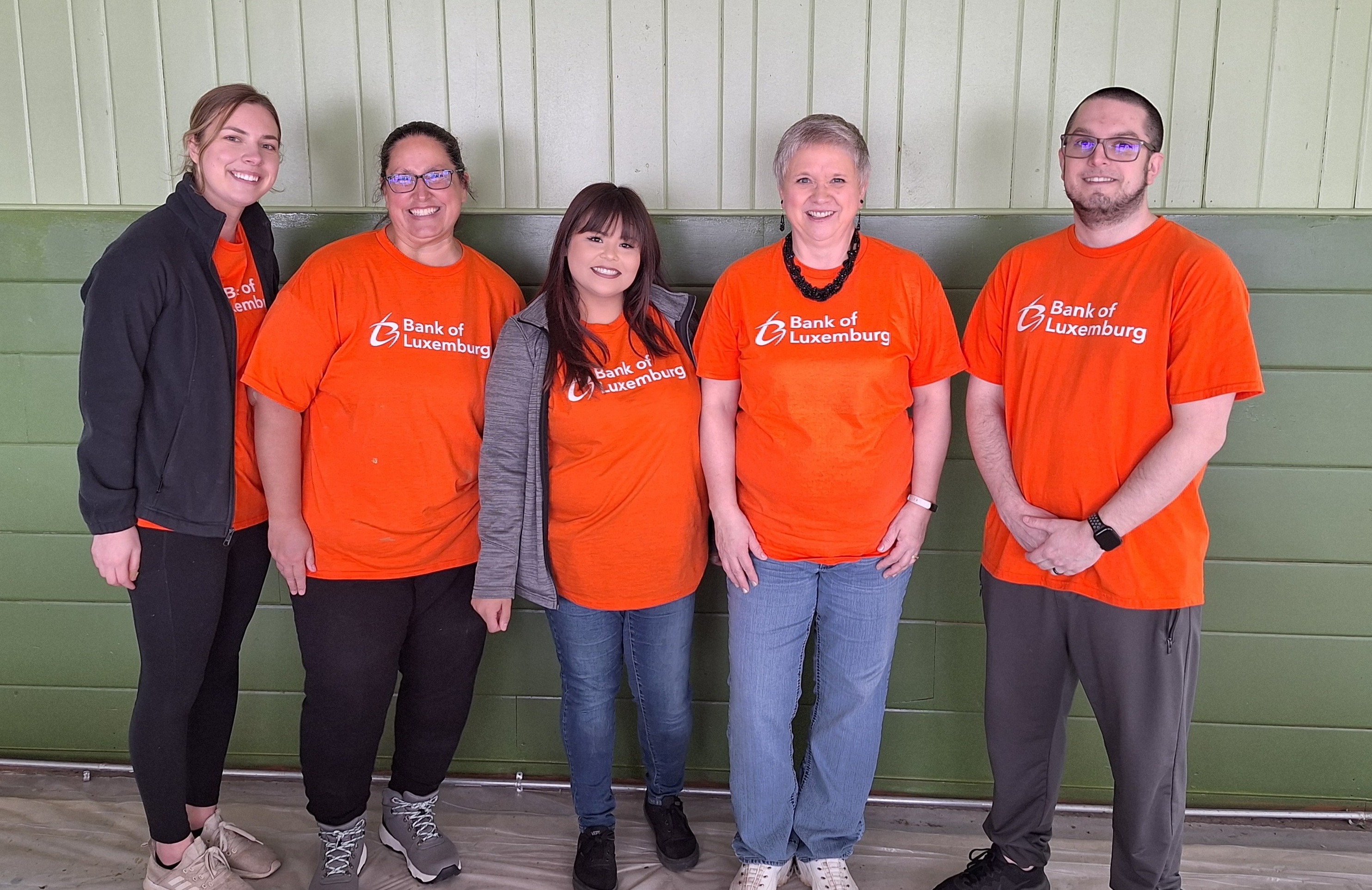 5 volunteers posing in front of green wall